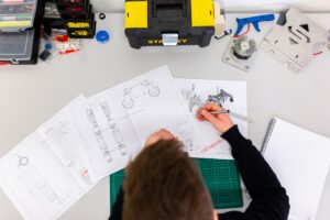 Robotics automation project scoping — engineer measuring robot design drawings with calipers